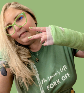 Photo of Kerry with lime green glasses, nails, shirt, and background to match her lime green cast on her left wrist. Shirt reads, "No spoons left - fork off"