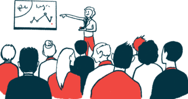 A person points to a chart on a wall in front of a conference audience.
