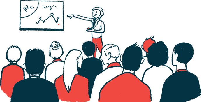 A person points to a chart on a wall in front of a conference audience.